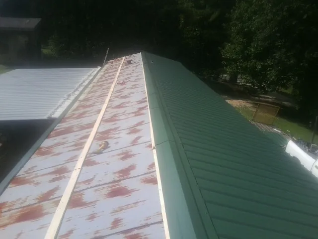 Old rusted panels beside newly installed green metal roofing — Wind Damage Roof Repair by Roofing Brothers in Brogue