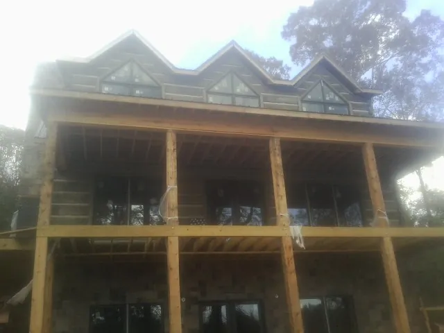 Dormers and porch framing on a large log home under construction — Roof Coating work by our crew in Brogue
