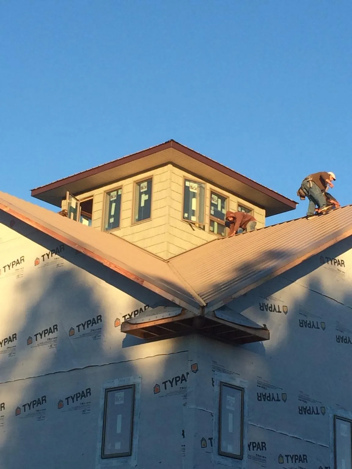 Roofers working around a rooftop cupola on a new metal roof at sunset — Roof Waterproofing in Brogue by Roofing Brothers